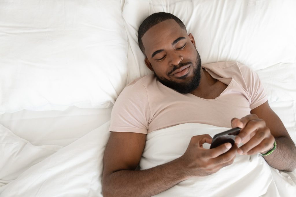 Man Texting in Bed
