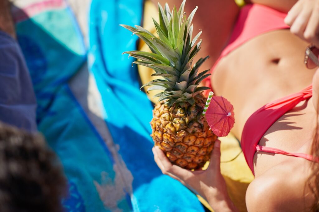 Woman in bikini holding a pineapple, a common swinger symbol or sign.