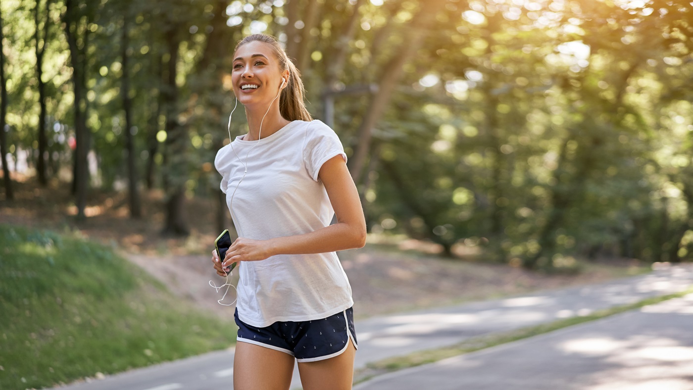 Woman with Earbuds Running in Park